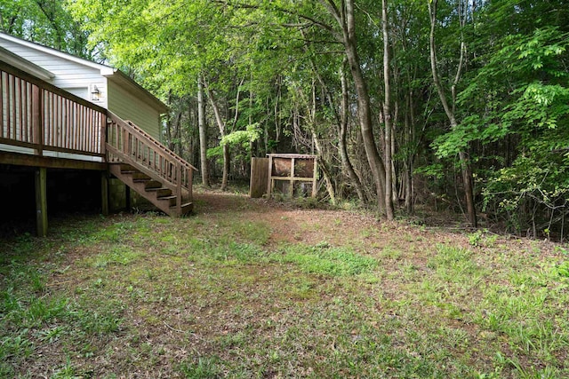 view of yard with stairway, a view of trees, and a wooden deck