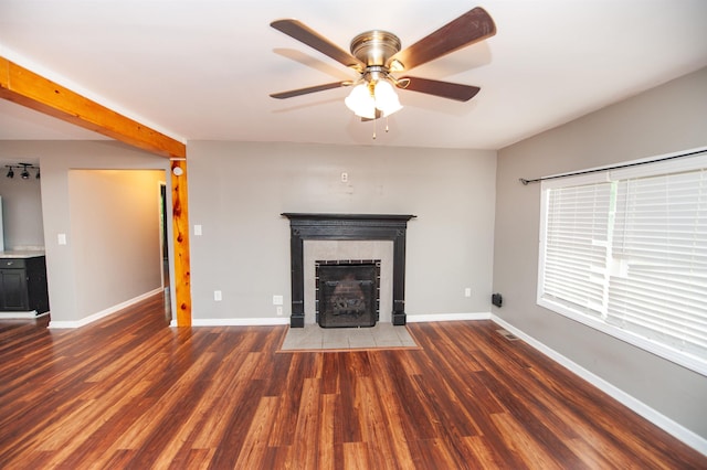 unfurnished living room featuring baseboards, ceiling fan, wood finished floors, and a fireplace