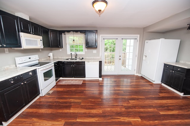 kitchen featuring white appliances, dark cabinetry, a sink, and dark wood-type flooring