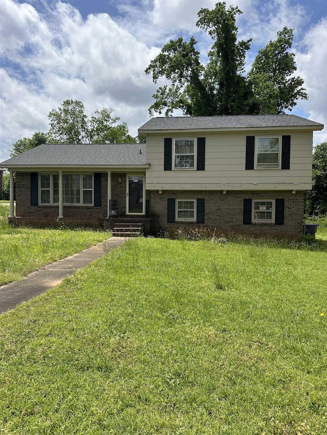 tri-level home with brick siding and a front yard