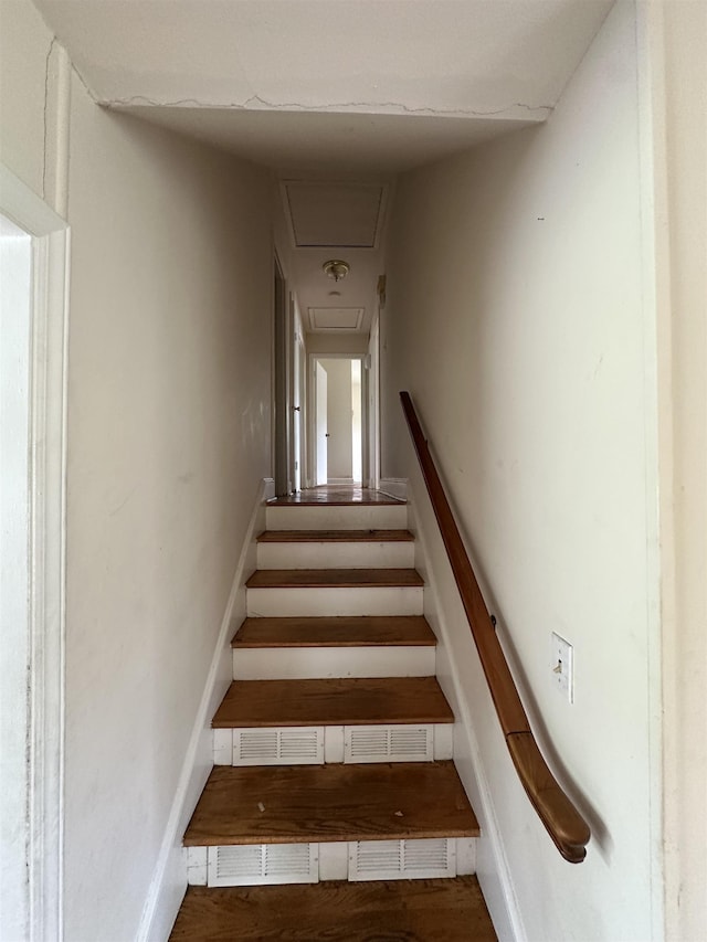 staircase featuring baseboards and attic access