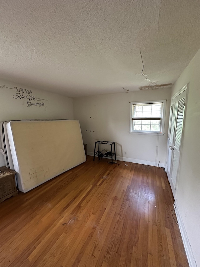empty room featuring baseboards, hardwood / wood-style flooring, and a textured ceiling