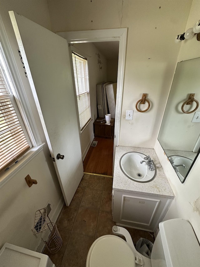 half bathroom featuring vanity, baseboards, tile patterned floors, and toilet