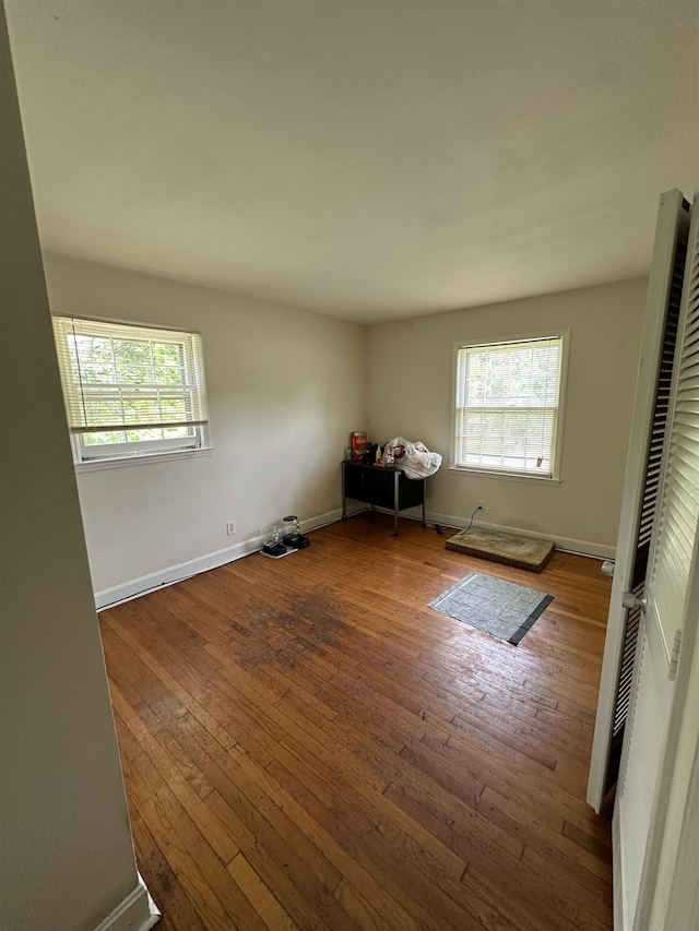 unfurnished bedroom with wood-type flooring, baseboards, and multiple windows