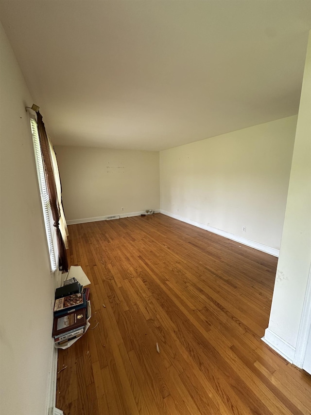 unfurnished living room with baseboards, wood finished floors, and visible vents