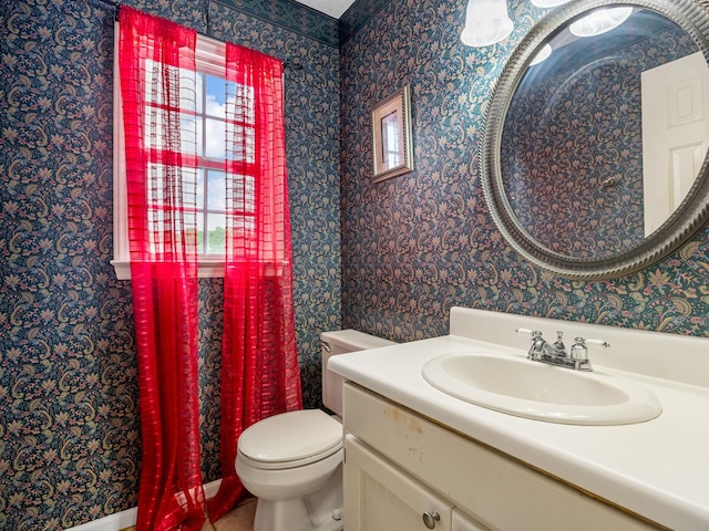 bathroom featuring vanity, toilet, and wallpapered walls