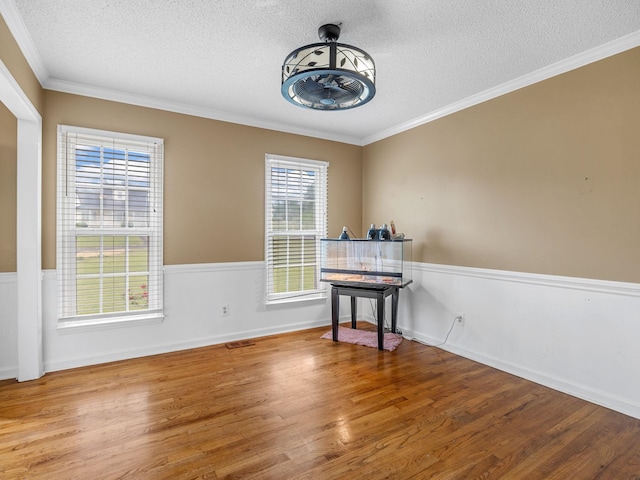 interior space with crown molding, visible vents, a textured ceiling, and wood finished floors