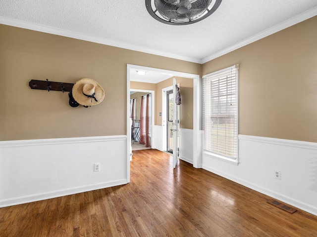 spare room with crown molding, a textured ceiling, and wood finished floors