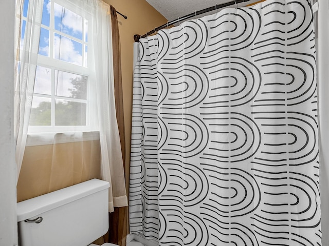 full bathroom with toilet and a shower with shower curtain