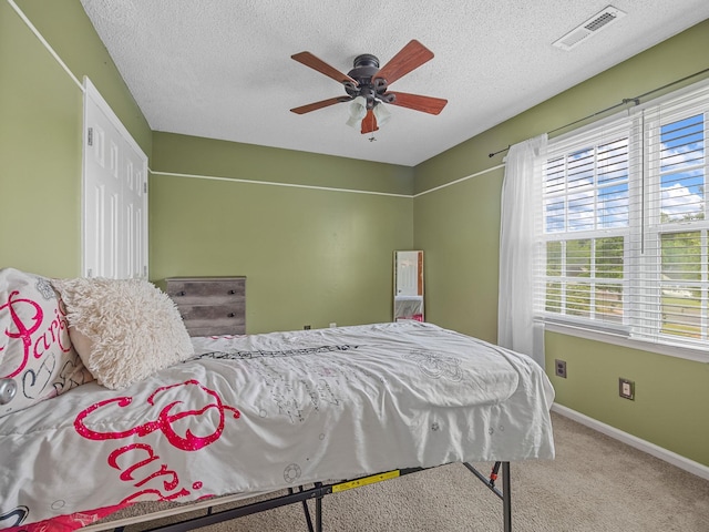 carpeted bedroom featuring baseboards, a ceiling fan, a textured ceiling, and visible vents