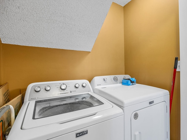 laundry area with a textured ceiling and washing machine and clothes dryer