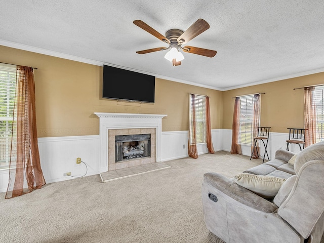 living room with a textured ceiling, a tile fireplace, and a wainscoted wall
