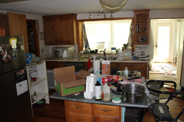 kitchen with freestanding refrigerator, wood finished floors, radiator heating unit, brown cabinets, and a sink