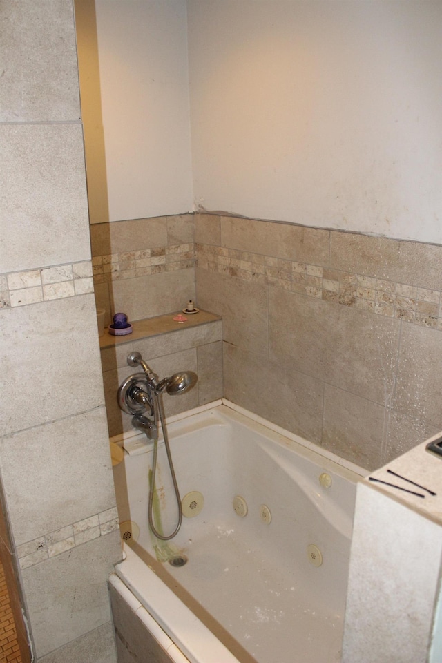 full bath with tile walls and a tub with jets