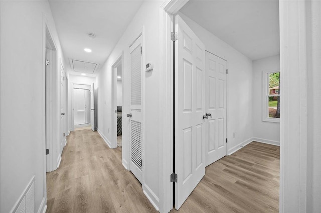 corridor featuring baseboards, attic access, light wood-style flooring, and visible vents