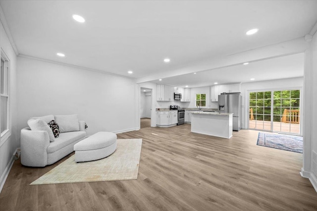 living area featuring crown molding, recessed lighting, baseboards, and light wood finished floors