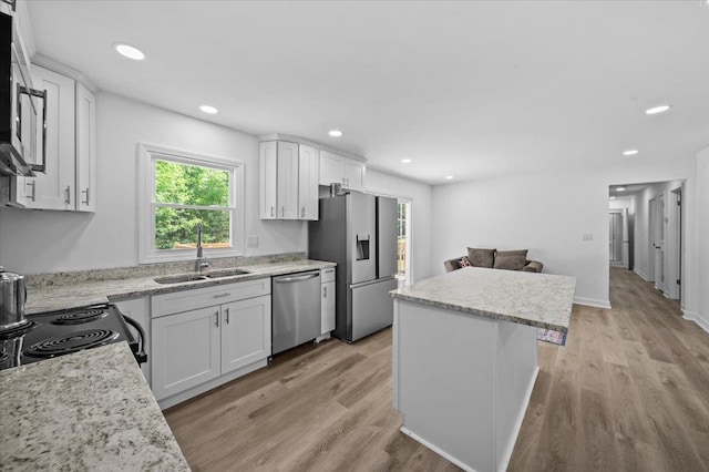 kitchen featuring a center island, a sink, a healthy amount of sunlight, and stainless steel appliances
