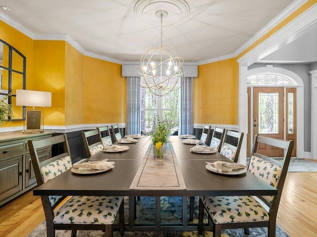 dining area with an inviting chandelier, ornamental molding, and light wood finished floors