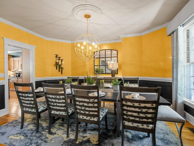 dining area with ornamental molding, wood finished floors, a notable chandelier, and a healthy amount of sunlight