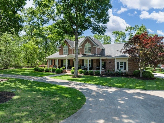 craftsman house featuring covered porch, brick siding, and a front yard