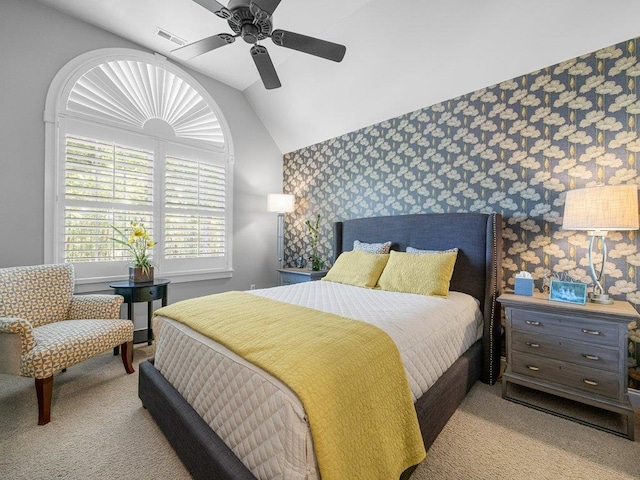 bedroom featuring carpet floors, an accent wall, wallpapered walls, vaulted ceiling, and visible vents