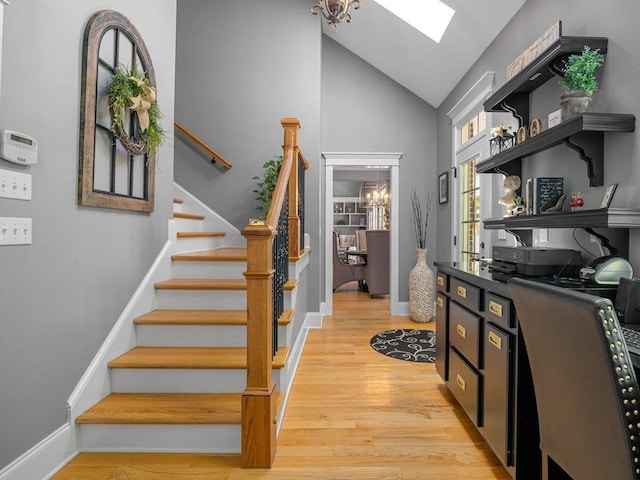 interior space with baseboards, wood finished floors, a skylight, and high vaulted ceiling