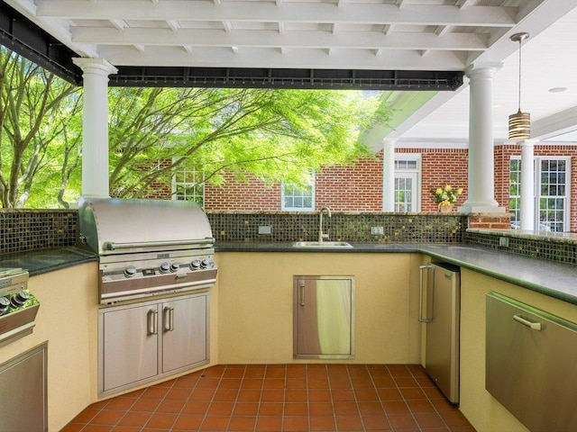 kitchen with ornate columns, dark countertops, a sink, and refrigerator