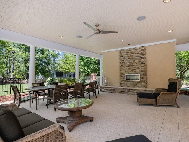 view of patio / terrace featuring outdoor dining area, a ceiling fan, an outdoor living space with a fireplace, and fence