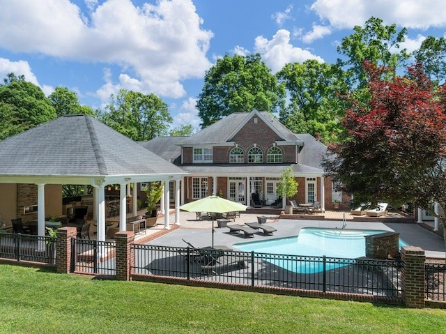 rear view of property featuring fence, a gazebo, a fenced in pool, a patio, and a yard