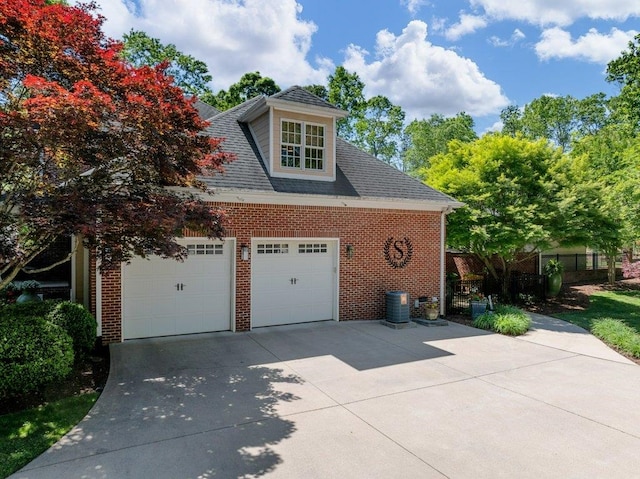 view of side of property featuring fence, roof with shingles, brick siding, a garage, and central AC unit