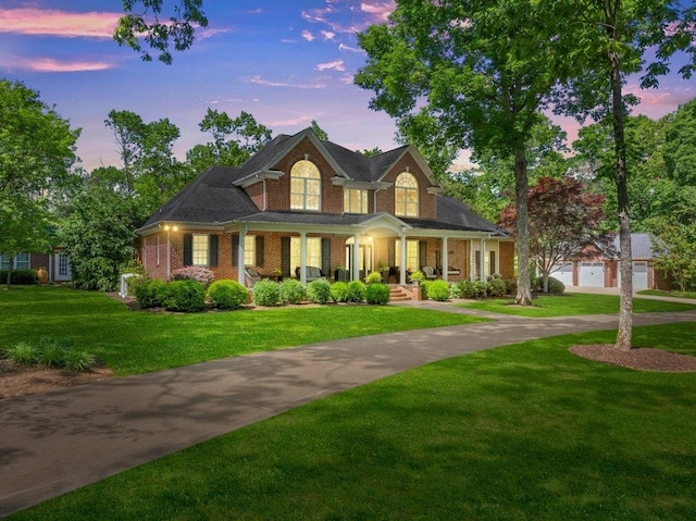 view of front facade featuring a lawn, a porch, and brick siding