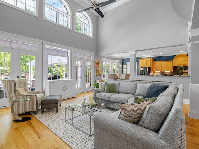 living area with crown molding, a high ceiling, a ceiling fan, and french doors