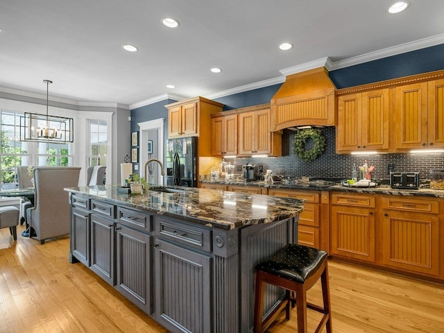 kitchen with a kitchen breakfast bar, a chandelier, decorative backsplash, a center island with sink, and black appliances