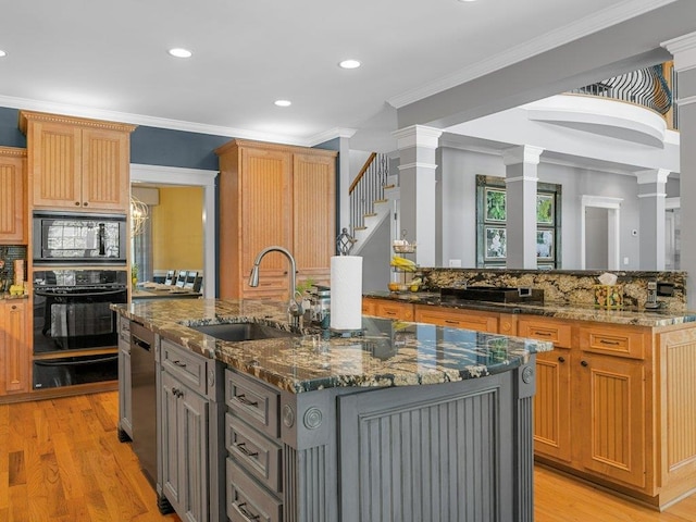 kitchen featuring a sink, a kitchen island with sink, black appliances, backsplash, and a warming drawer