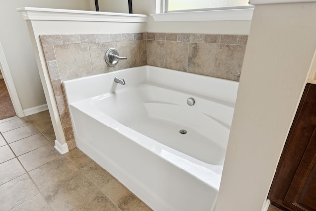 bathroom featuring baseboards, tile patterned flooring, and a garden tub