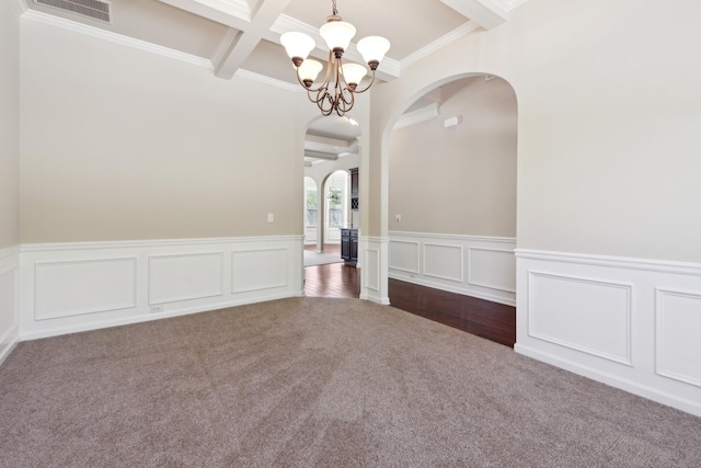 spare room featuring visible vents, arched walkways, beamed ceiling, a notable chandelier, and dark carpet
