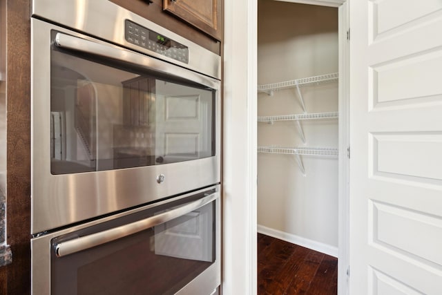 interior space featuring dark wood finished floors, baseboards, and stainless steel double oven