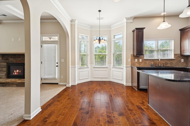 kitchen with dark brown cabinets, hanging light fixtures, a sink, dark stone countertops, and dark wood-style floors