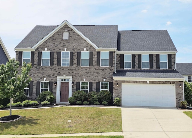 colonial home featuring roof with shingles, an attached garage, driveway, and a front yard