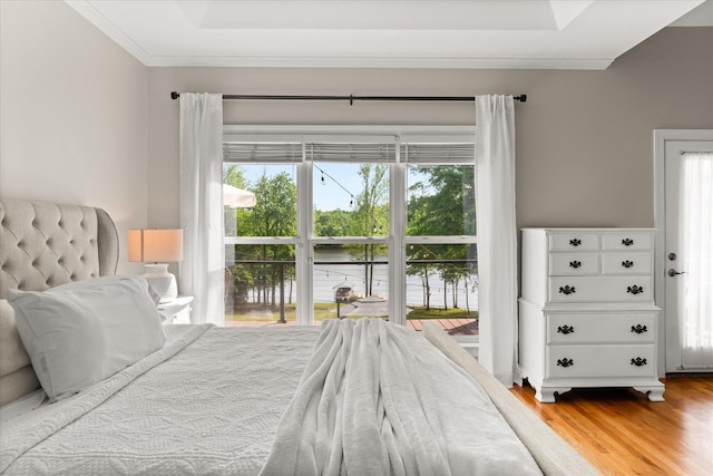 bedroom with crown molding, a water view, multiple windows, and wood finished floors