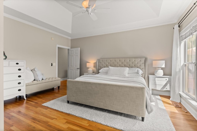 bedroom featuring crown molding, a raised ceiling, ceiling fan, and wood finished floors