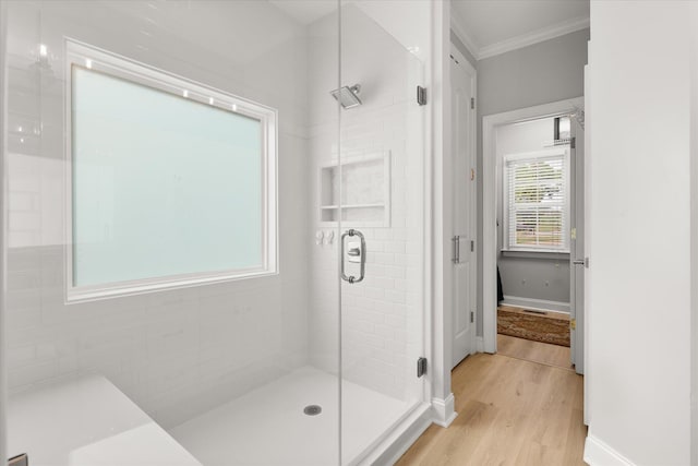 bathroom with crown molding, baseboards, a shower stall, and wood finished floors