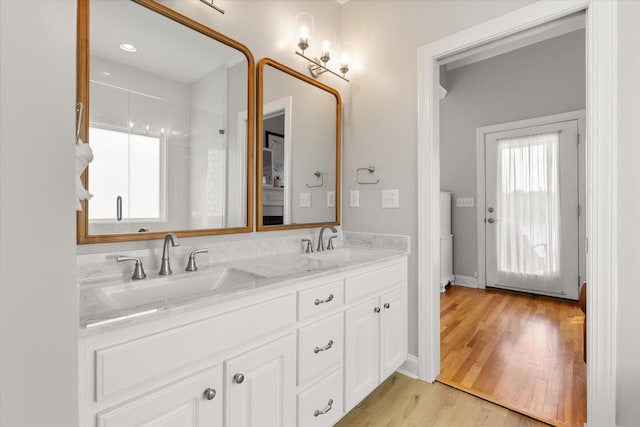 full bath featuring double vanity, a sink, and wood finished floors