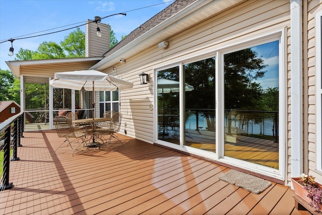 wooden terrace with a sunroom and outdoor dining space