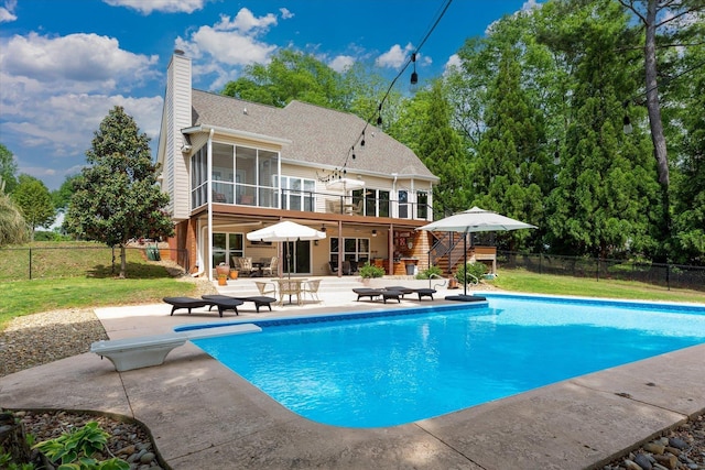 back of property with a sunroom, a patio area, fence, a fenced in pool, and stairs