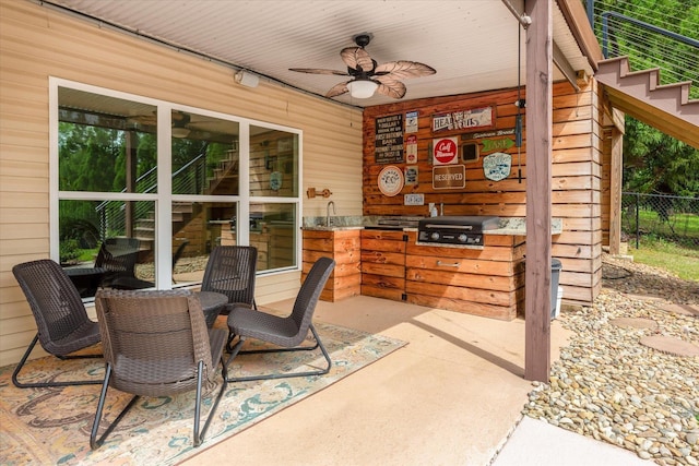 view of patio with ceiling fan, fence, an outdoor kitchen, and area for grilling