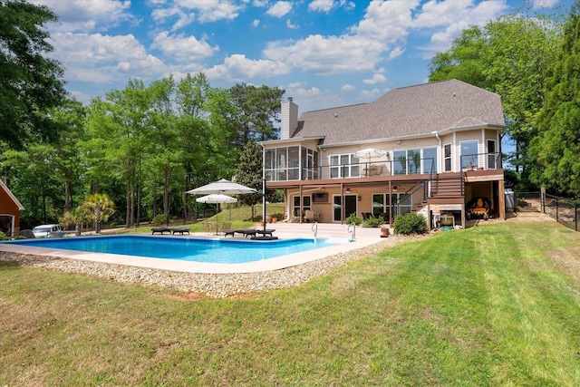 rear view of house with a chimney, a sunroom, a patio area, a yard, and stairs