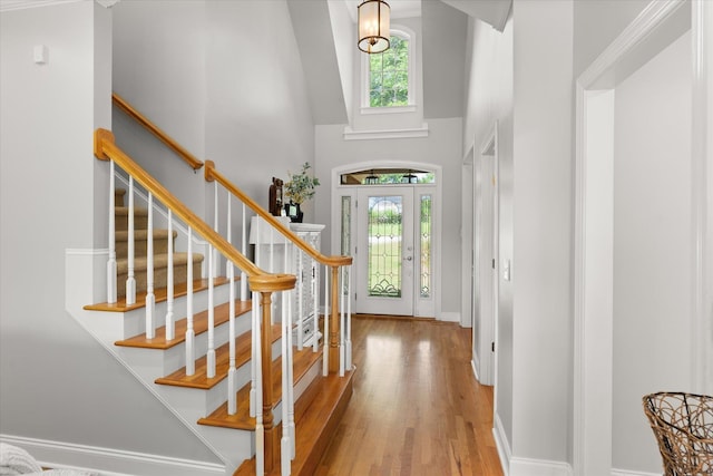 foyer entrance with wood finished floors, baseboards, stairs, and a high ceiling