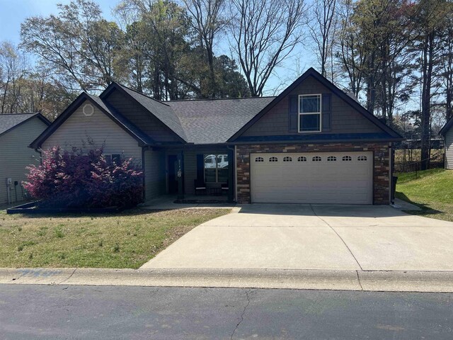 craftsman-style house featuring driveway, roof with shingles, a front yard, a garage, and stone siding