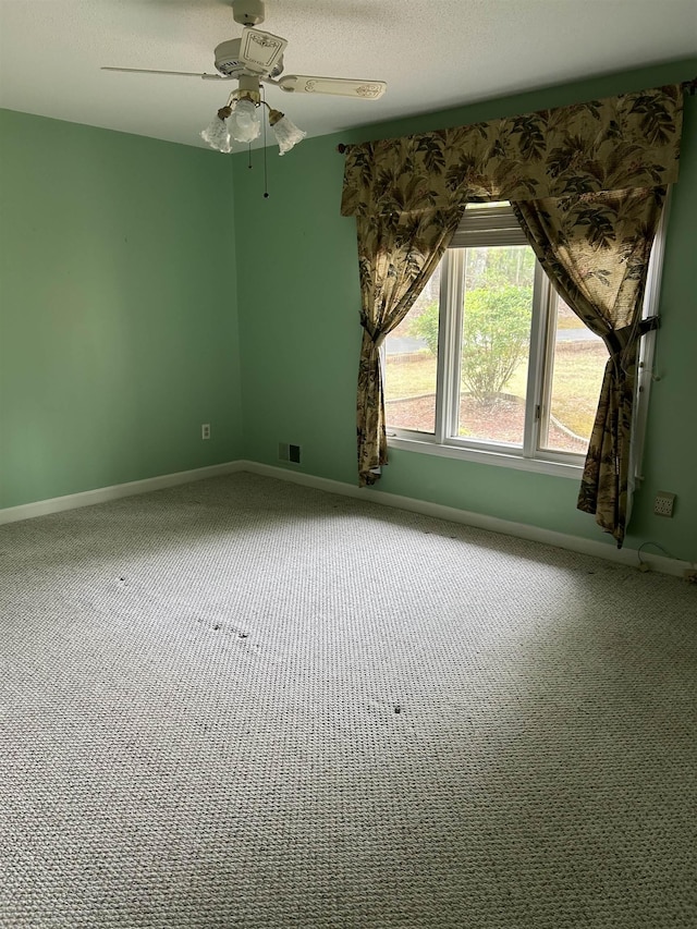 spare room featuring carpet floors, a ceiling fan, baseboards, and visible vents